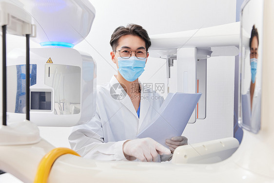 手拿资料调试仪器的牙科医生图片