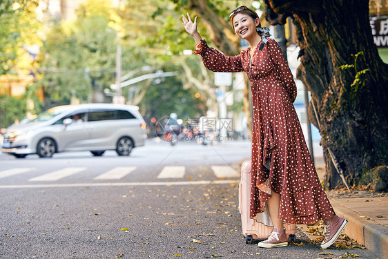 清新美女出游拉着行李箱路边叫车图片