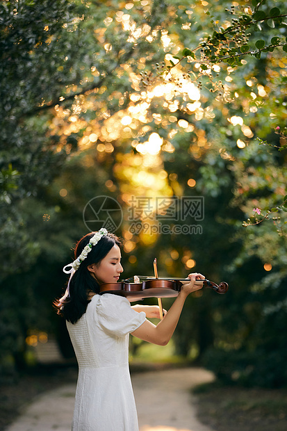 夕阳余晖中拉小提琴的少女图片