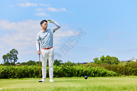 男性手握高尔夫球杆眺望远方图片