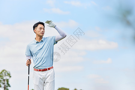 男性手握高尔夫球杆眺望远方图片
