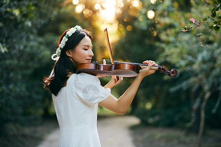 夕阳余晖中拉小提琴的少女背景图片