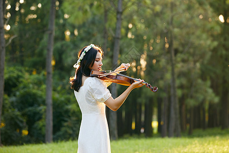 夕阳余晖中拉小提琴的少女背影高清图片