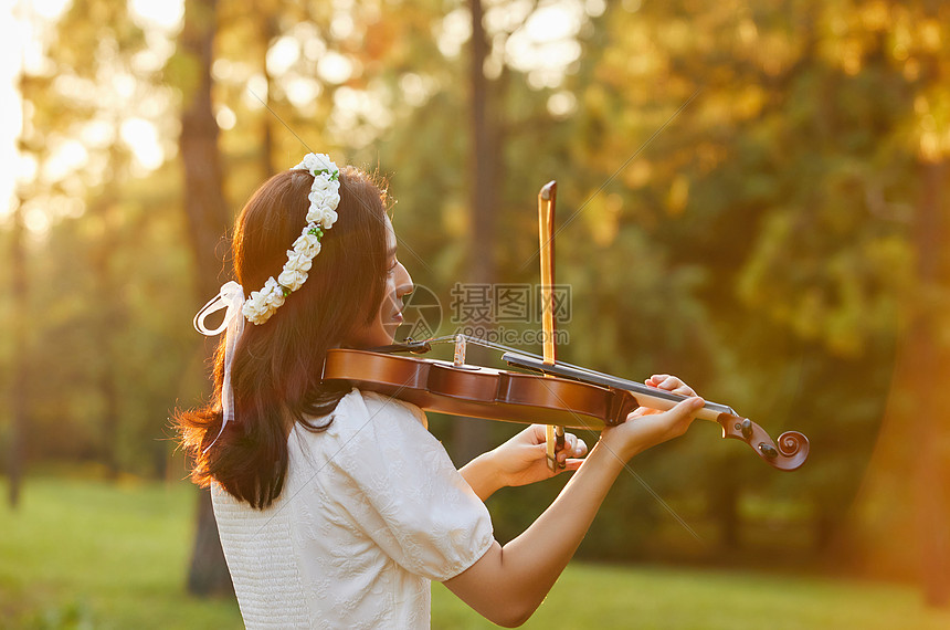 夕阳余晖中拉小提琴的少女背影图片
