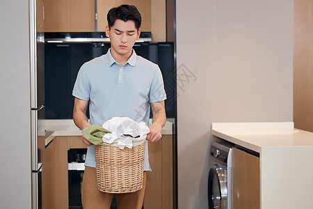 脏脏蛋糕年轻男性在家里端着脏衣服背景