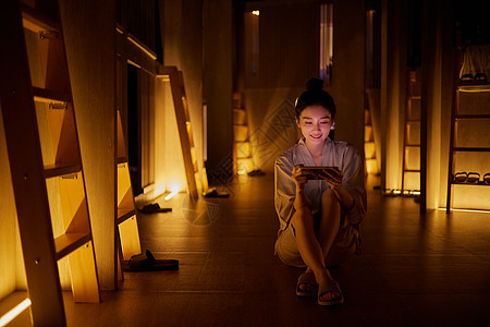 青年女性在汤泉馆休息区玩手机游戏图片