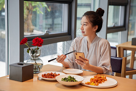 秋季饮食青年美女在汤泉馆美食区吃饭玩手机背景
