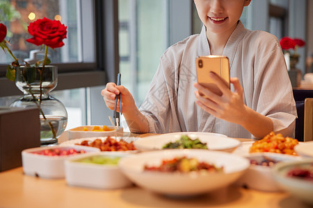 秋季饮食青年女性在汤泉馆吃饭玩手机特写背景