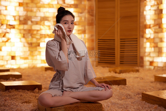 在桑拿房用毛巾擦汗的青年女性图片