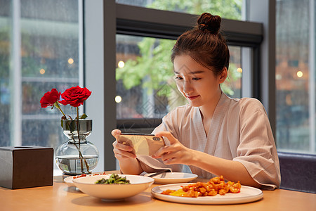 青年女性吃饭用手机拍照记录美食图片