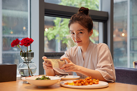 青年女性吃饭用手机拍照记录图片