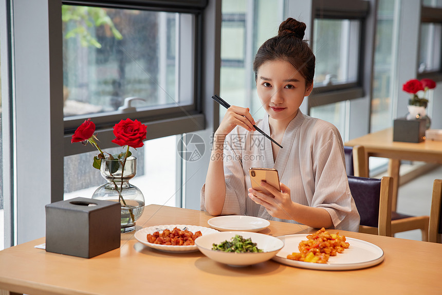 在汤泉馆美食区吃饭玩手机的青年女性图片