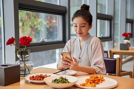 在汤泉馆美食区吃饭玩手机的青年女性图片