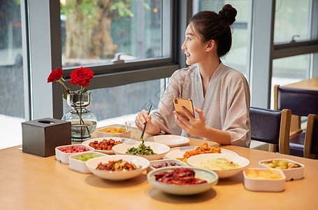 青年女性在汤泉馆吃饭玩手机图片