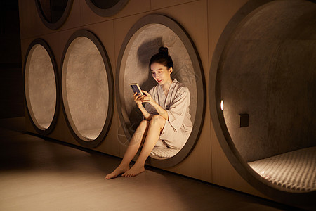 桑拿馆休息区玩手机的年轻女性图片