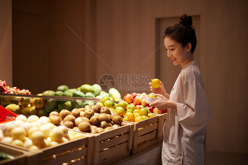 在美食区挑选水果的女性图片