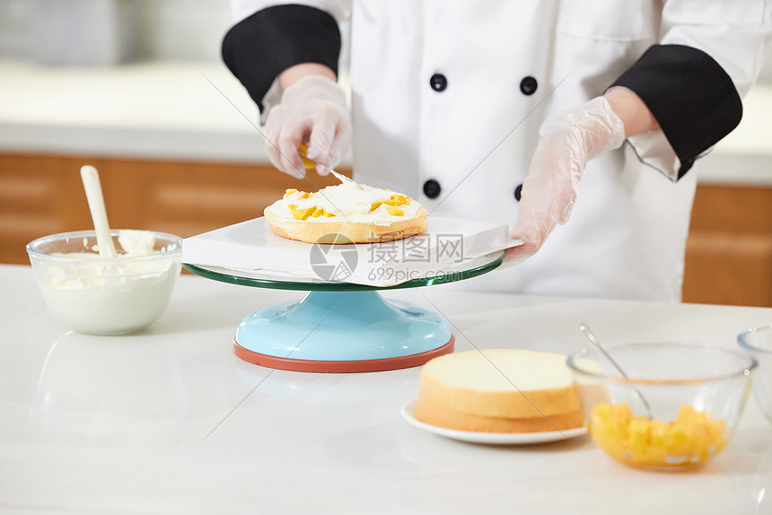 烘焙师往蛋糕胚上抹奶油特写图片