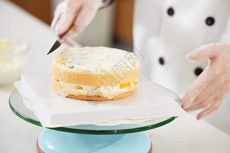 女性烘焙师往蛋糕上抹奶油特写图片
