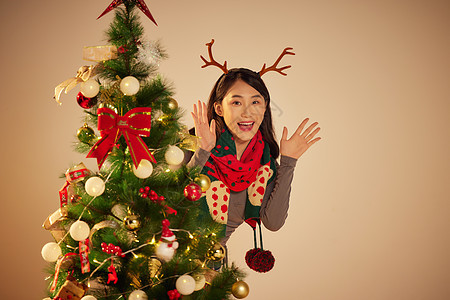圣诞节美女开心的躲在圣诞树后图片