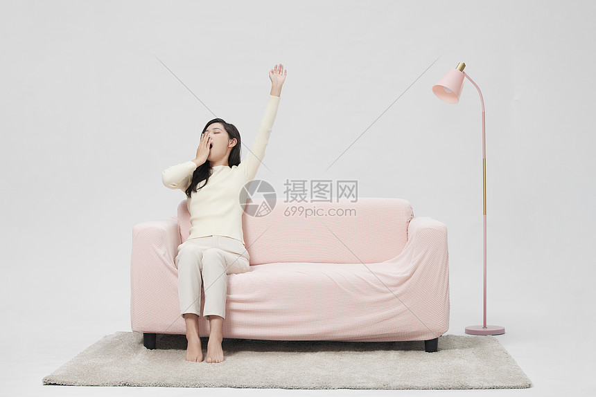 睡眠不足的女性在沙发上伸懒腰图片
