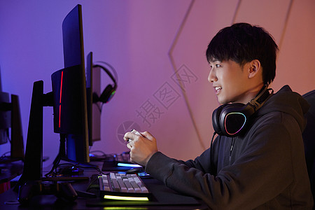 青年男性坐电脑前拿游戏手柄打游戏图片