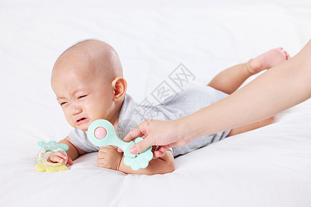 手拿玩具逗哭泣的宝宝图片