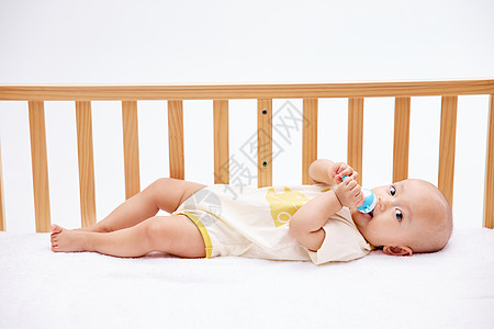 可爱宝宝在婴儿床里吃奶嘴图片