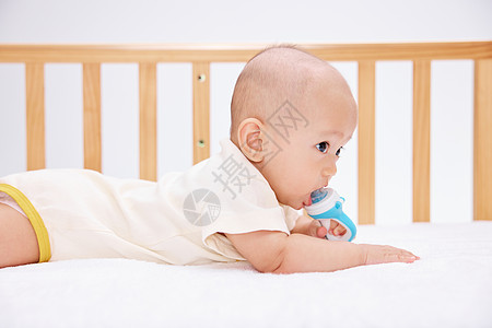 可爱宝宝在婴儿床里吃奶嘴爬行图片