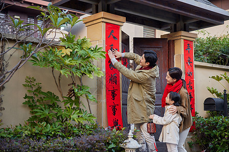 一家三口春节家门口贴对联背景图片