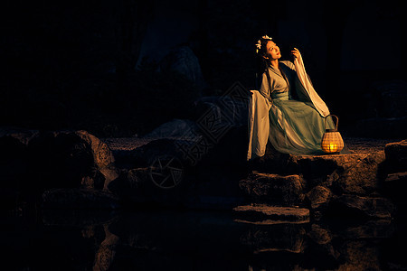 坐在河畔的汉服美女提着灯笼背景图片