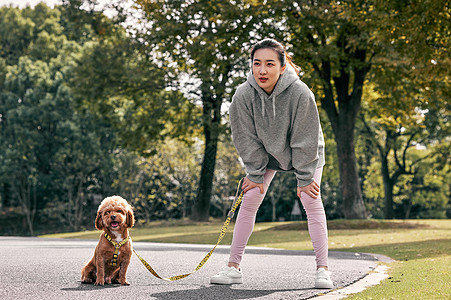 在公园牵着狗跑步休息的少女图片