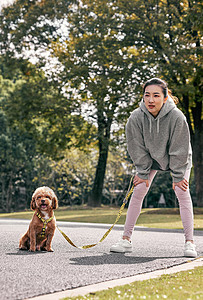 在公园牵着狗跑步休息的少女图片