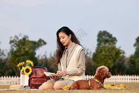 草地上睡觉的狗和看书的美女图片
