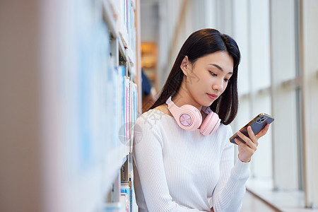 女学生在图书馆看书玩手机图片