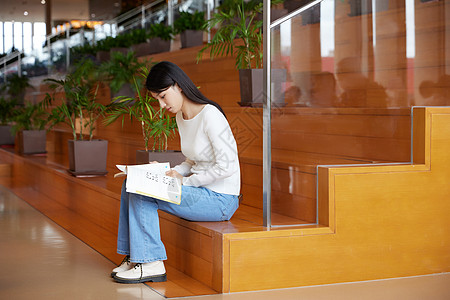 坐在图书馆台阶上看书的女学生图片