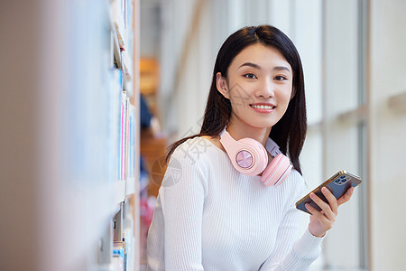 女学生在图书馆看书玩手机图片