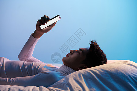 色彩创意男性躺着玩手机图片