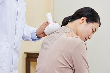 患者医生男中医给女顾客肩部使用艾草理疗背景