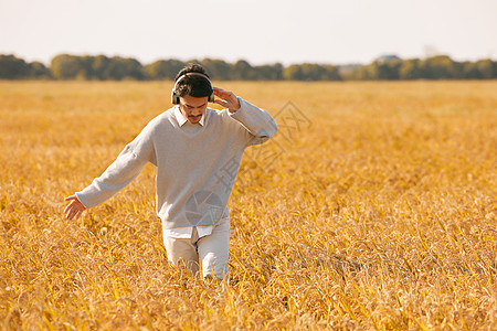水稻成熟戴着耳机走在稻田里的男性形象背景
