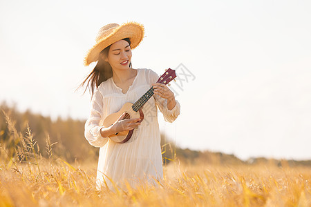 在稻田里弹奏尤克里里的女性图片