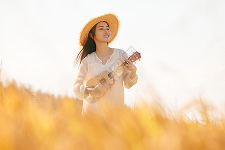 稻田水稻在稻田里弹奏尤克里里的女性背景