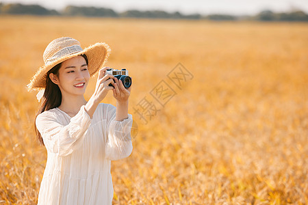 拿着照相机站在稻田里的女性图片