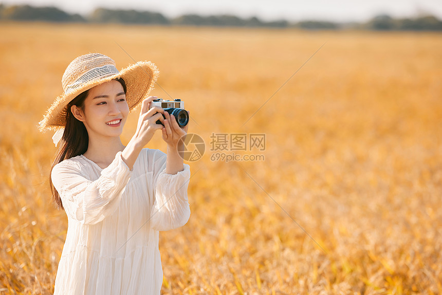 拿着照相机站在稻田里的女性图片