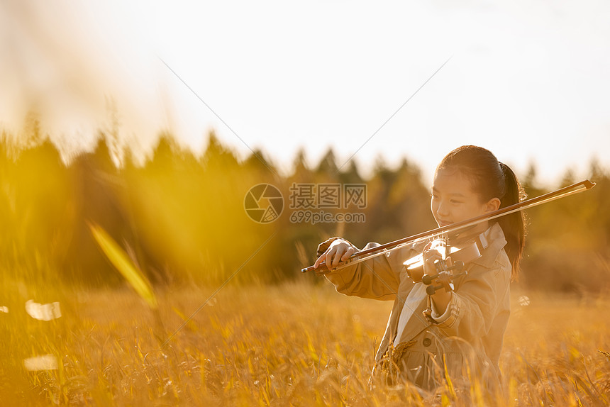 小女孩在田野里演奏小提琴图片
