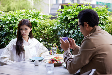 女性不高兴男性约会吃饭玩手机图片