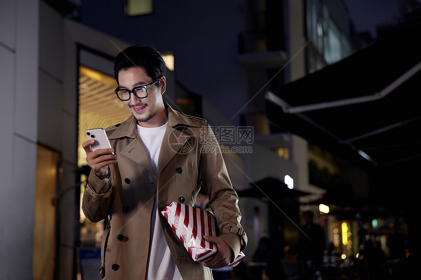 夜晚手拿礼物约会等候的青年男性图片