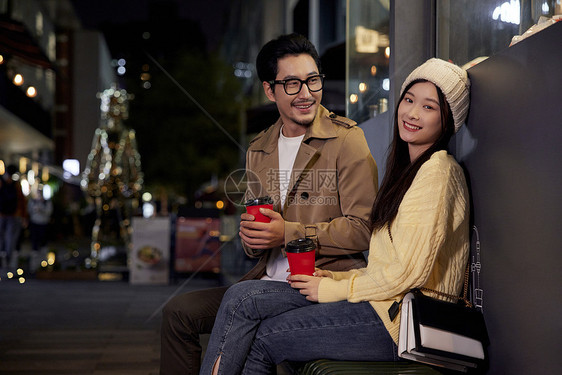 冬日夜晚街边喝咖啡聊天的青年情侣形象图片