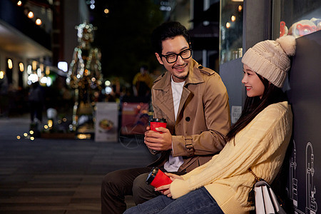 冬日夜晚街边喝咖啡聊天的青年情侣图片
