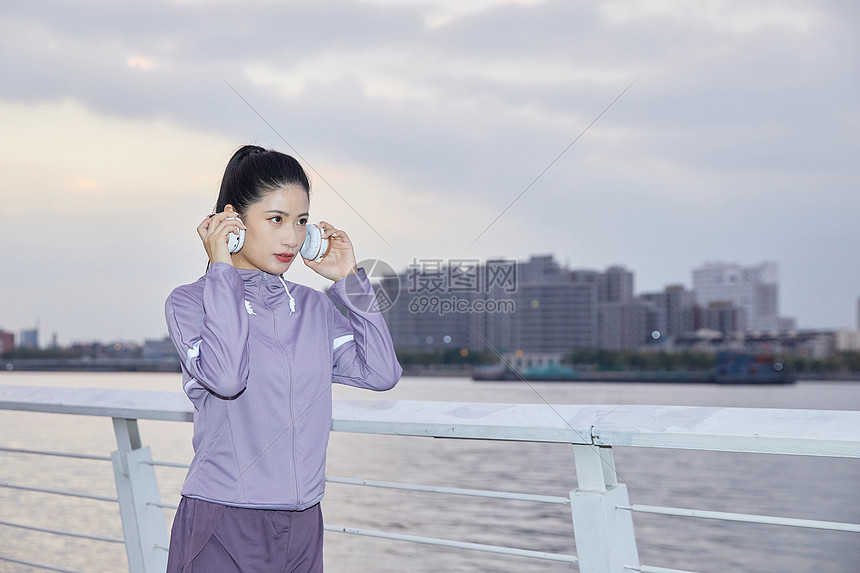 美女在江边戴耳机准备跑步图片