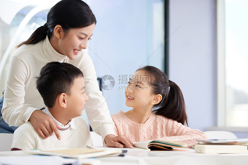 年轻女老师辅导小朋友学习图片